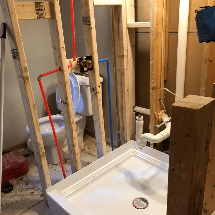 New framing, plumbing rough-in and a shower base set in a gutted bathroom