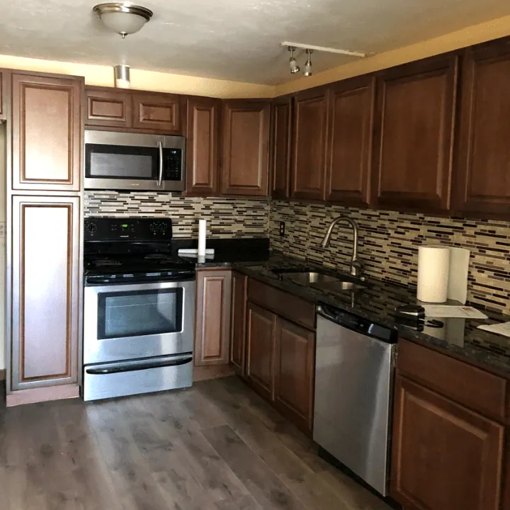 Kitchen with cherry cabinets, black granite counters, a glass mosaic backsplash and stainless appliances